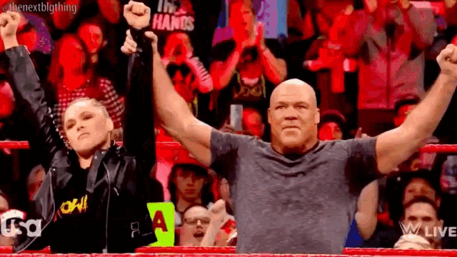 a man and a woman are raising their hands in the air in front of a crowd .
