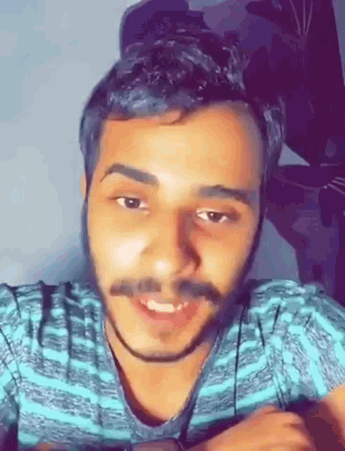 a man with a beard and mustache is wearing a blue striped shirt .