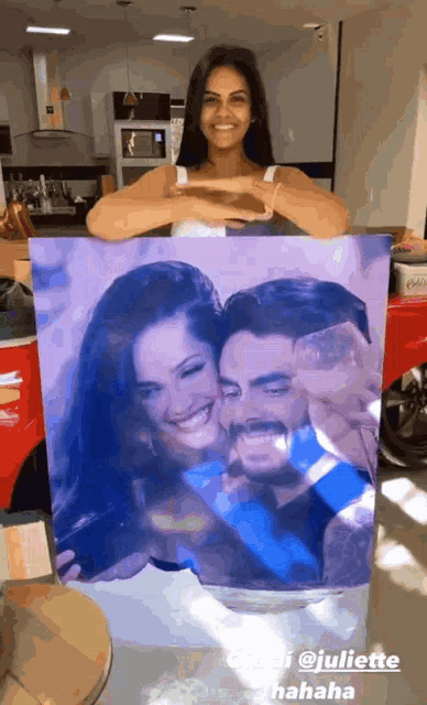 a woman holding up a painting of a man and woman