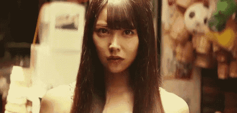 a woman with long hair and bangs is looking at the camera in a room .