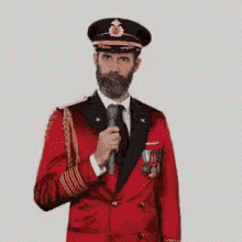 a man in a red jacket and black hat is holding a microphone .