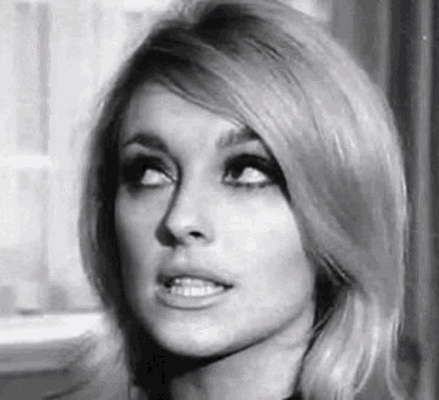 a black and white photo of a woman with blonde hair and a smile on her face .