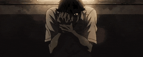 a man is sitting in a dark room with his hands on his face and his mouth open .