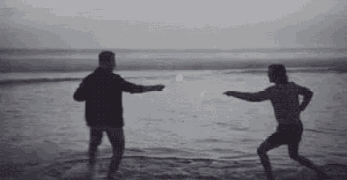 a man and a woman are playing with a ball on the beach .
