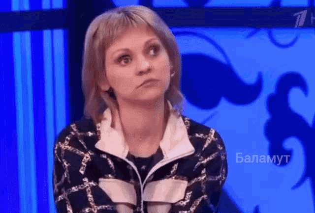 a woman is sitting in front of a blue screen with the word balamut written on it