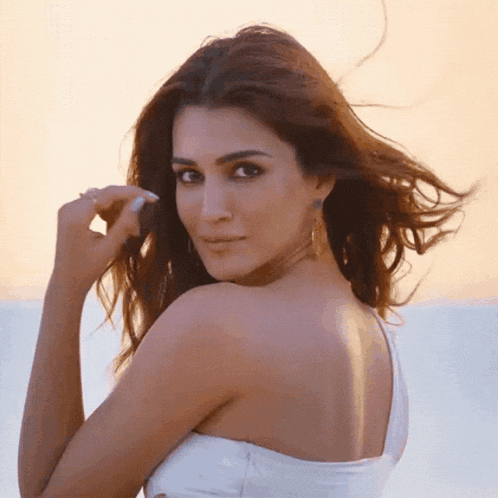 a woman in a white dress looks over her shoulder at the camera