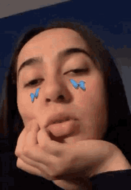 a girl with blue butterflies on her face is making a face .