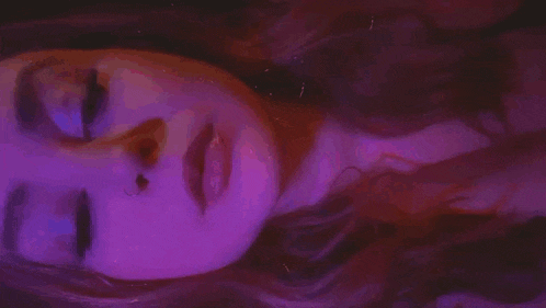 a close up of a person 's face in a dark room with purple and red smoke coming out of it .