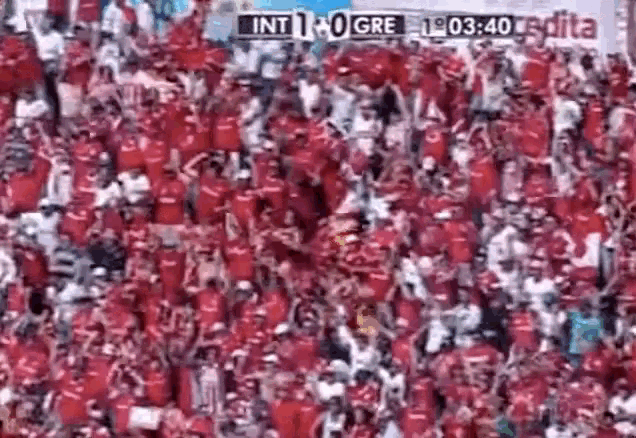 a crowd of people are watching a soccer game and the score is int 1-0 gre