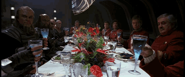 a group of people sitting at a long table toasting
