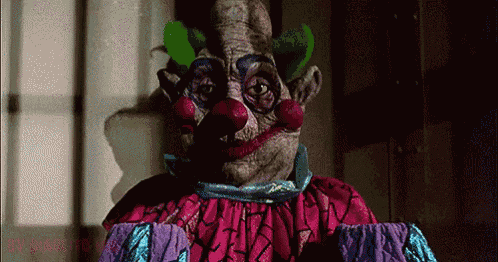 a clown in a purple and blue outfit is standing in front of a window