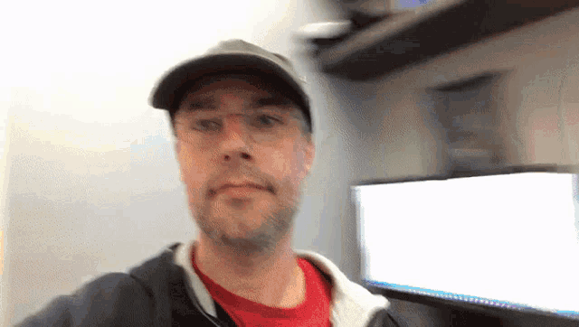 a man wearing glasses and a baseball cap is taking a selfie