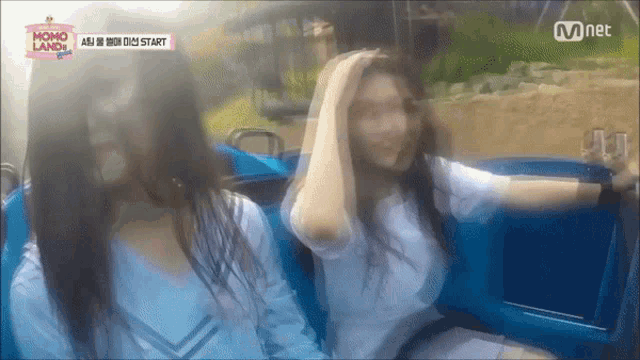 two girls are riding a roller coaster with a sign that says momo land on it