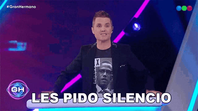 a man in a suit is standing in front of a sign that says " les pido silencio "