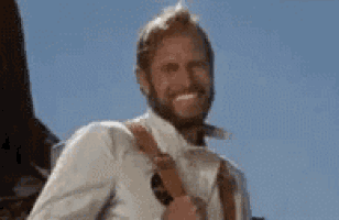 a man with a beard is smiling while carrying a backpack on his back .