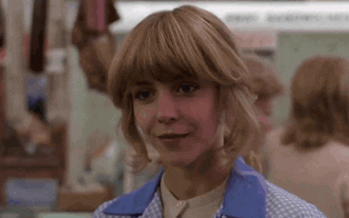 a woman with blonde hair and bangs is wearing a blue shirt and a white shirt .