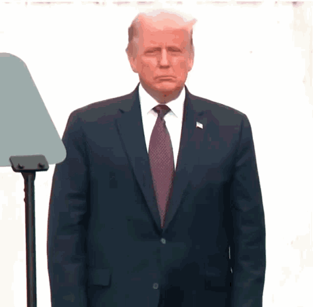 a man in a suit and tie stands in front of a podium with a white background