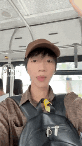 a man wearing a brown hat and a black backpack is taking a selfie on a bus .