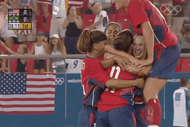 a group of soccer players hugging each other in front of a scoreboard that says usa bra