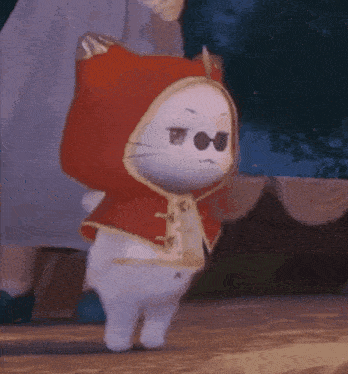 a white cat wearing a red hooded cape and sunglasses .