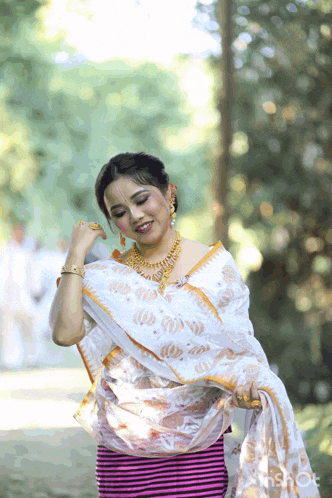 a woman wearing a white saree and a gold necklace