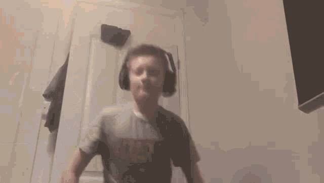 a young boy wearing headphones and a marvel shirt is dancing .