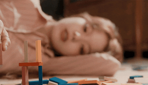 a child is laying on the floor playing with blocks