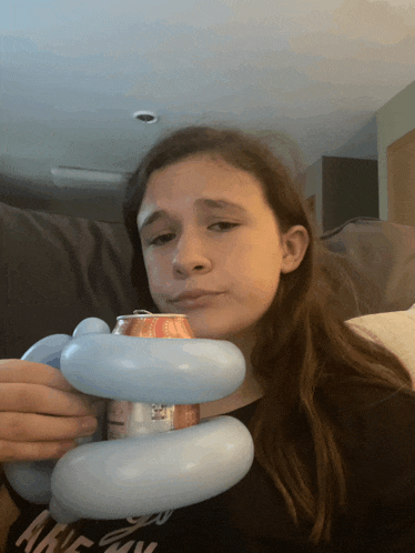 a girl is holding a can of soda with a balloon around it