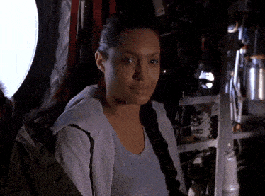 a woman wearing a white shirt and a braided ponytail looks at the camera