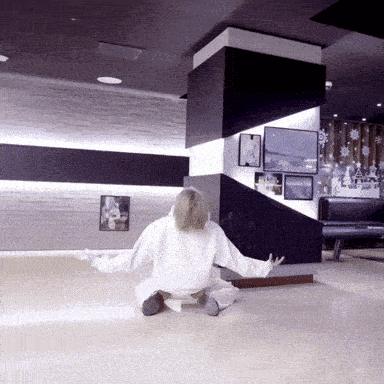 a woman is sitting on the floor with her arms outstretched in a room with pictures on the wall