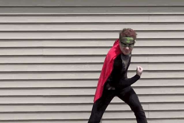 a young boy in a superhero costume is standing in front of a building .