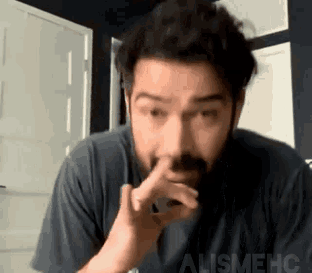a man with a beard is wearing a black shirt that says alismehc on the bottom