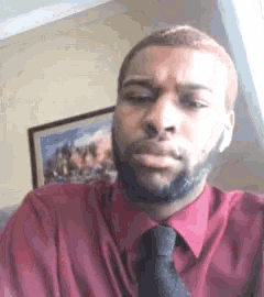a man in a red shirt and tie is making a funny face .