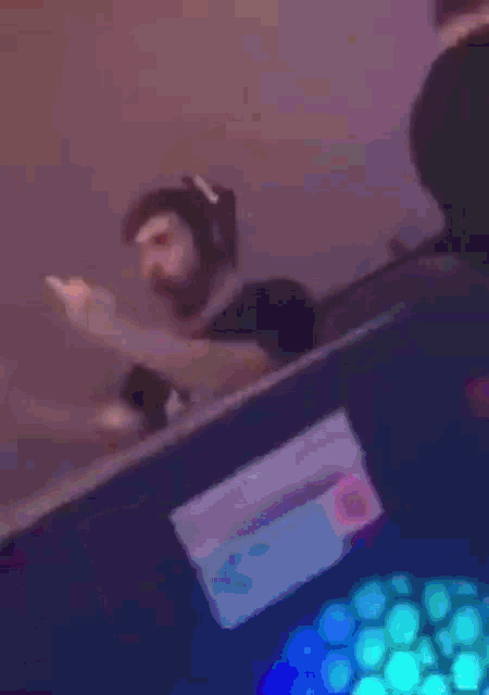 a blurry picture of a man wearing headphones and pointing at the camera .