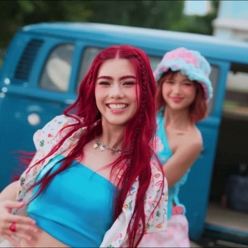 a woman with red hair is smiling next to another woman in a pink hat