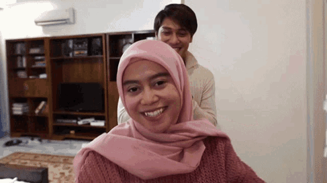 a man is putting a pink hijab on a woman