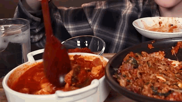 a person is stirring a bowl of food with a wooden spoon ..