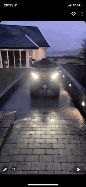 a red atv is parked on a brick driveway in front of a house