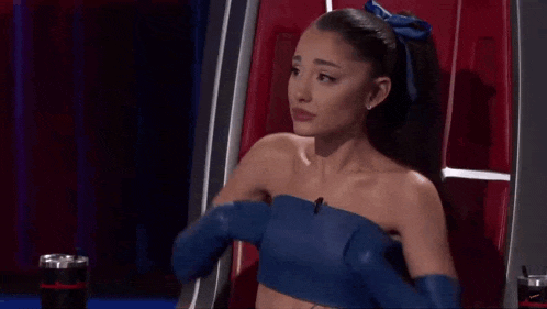 a woman wearing a blue top and gloves is sitting in a chair