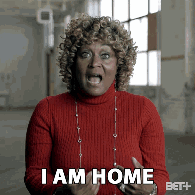 a woman in a red sweater and necklace says i am home