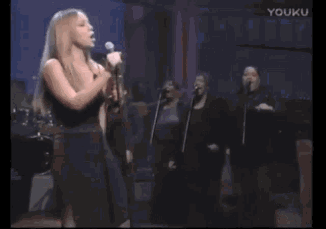 a woman is singing into a microphone and laughing while another woman stands behind her .