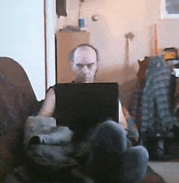 a man sits on a couch using a laptop
