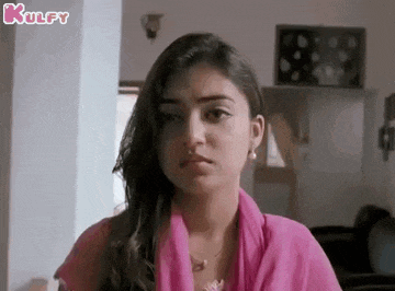 a woman in a pink dress is making a funny face in a room .