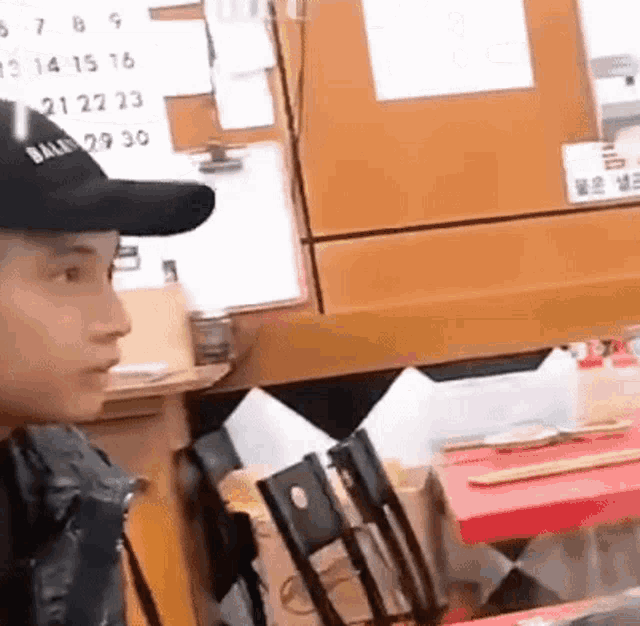 a man wearing a hat is sitting at a table in a restaurant with a calendar on the wall .