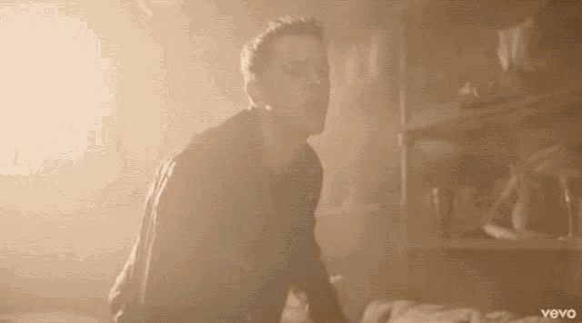 a man is standing in a dark room with smoke coming out of his mouth .