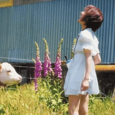 a woman in a white dress stands in front of a cow