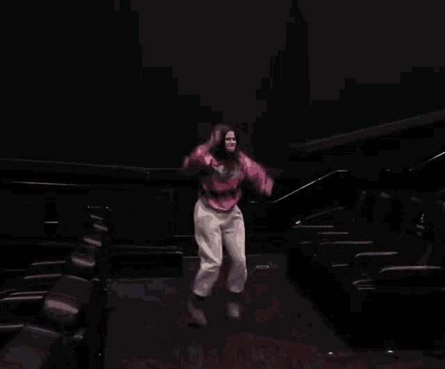 a woman is dancing in a dark room wearing a sweater that says ' a' on it