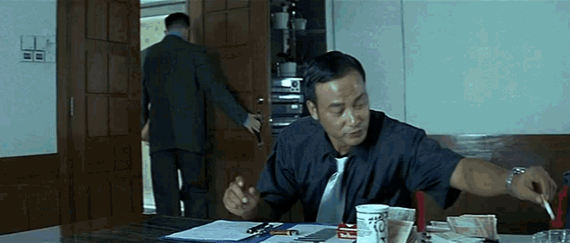 a man is sitting at a table with a cup that has the number 10 on it