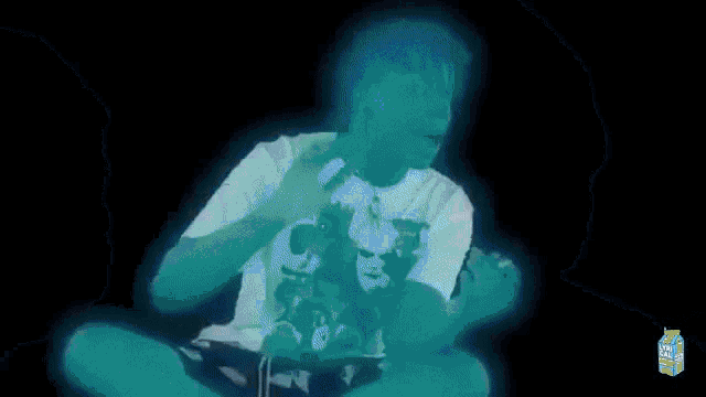 a man in a white shirt is glowing in the dark and holding a toy .