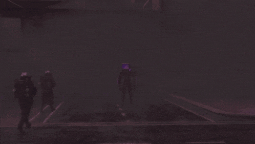 a group of people walking in a foggy area with a purple figure in the middle